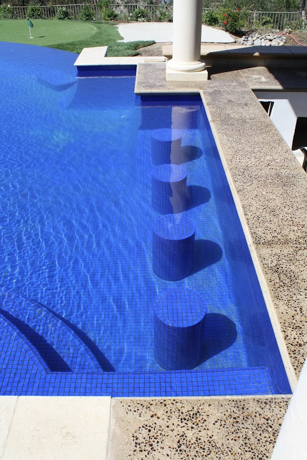 swim-up bar in a blue pool in a backyard private water park