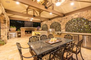 Outdoor kitchen with wine bottle wall, lighting, and outdoor sound speakers in the ceiling